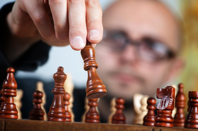 Eine Hand bewegt eine Spielfigur auf einem Brettspiel